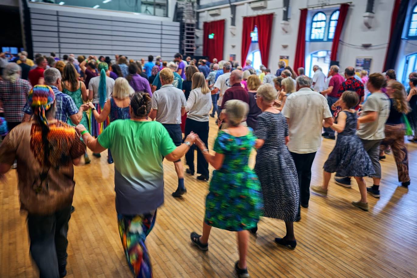 Lines of dancers hold hands during a social dance at the Neeld